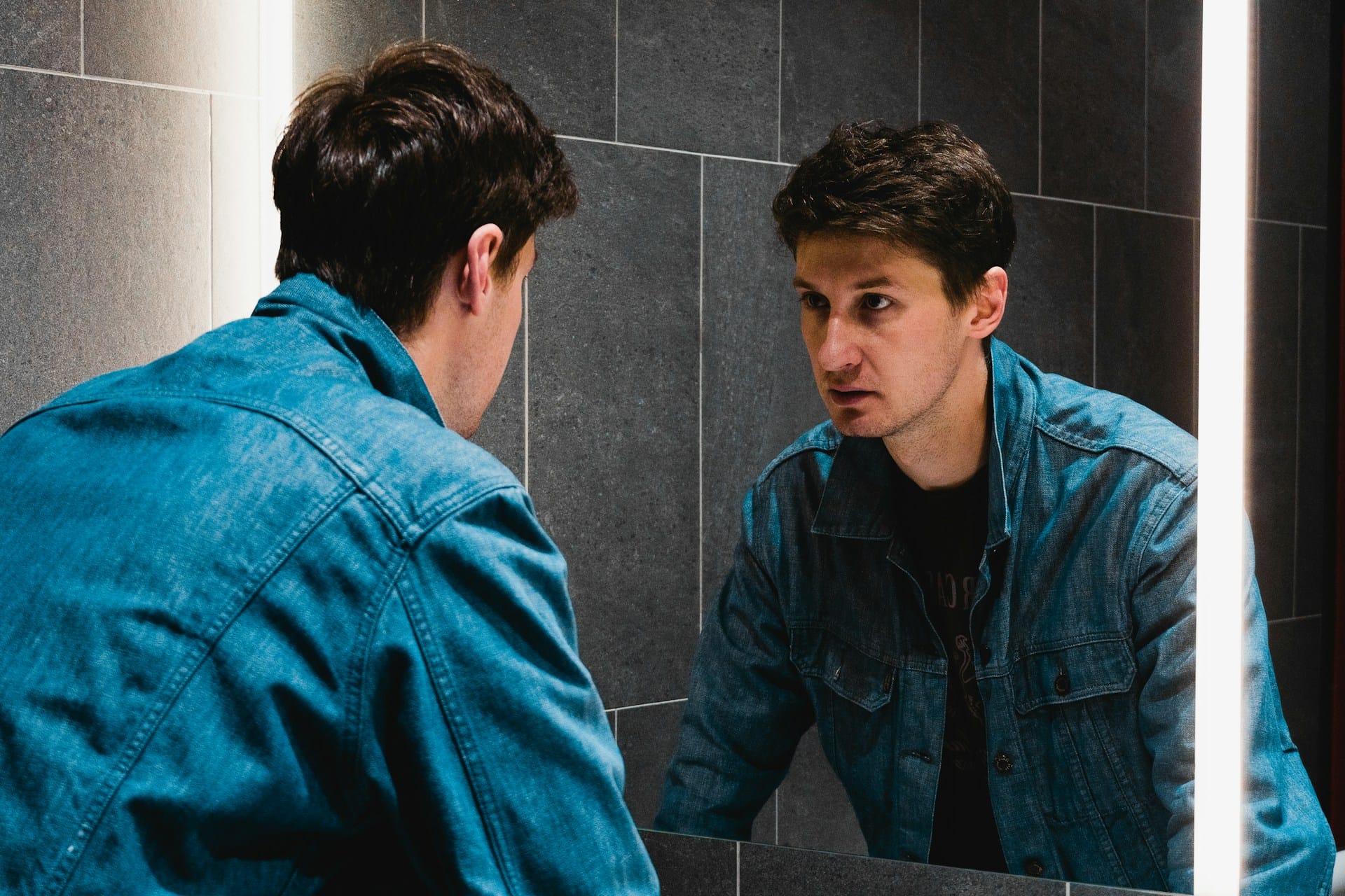 Un homme se penche et regarde son reflet dans un miroir