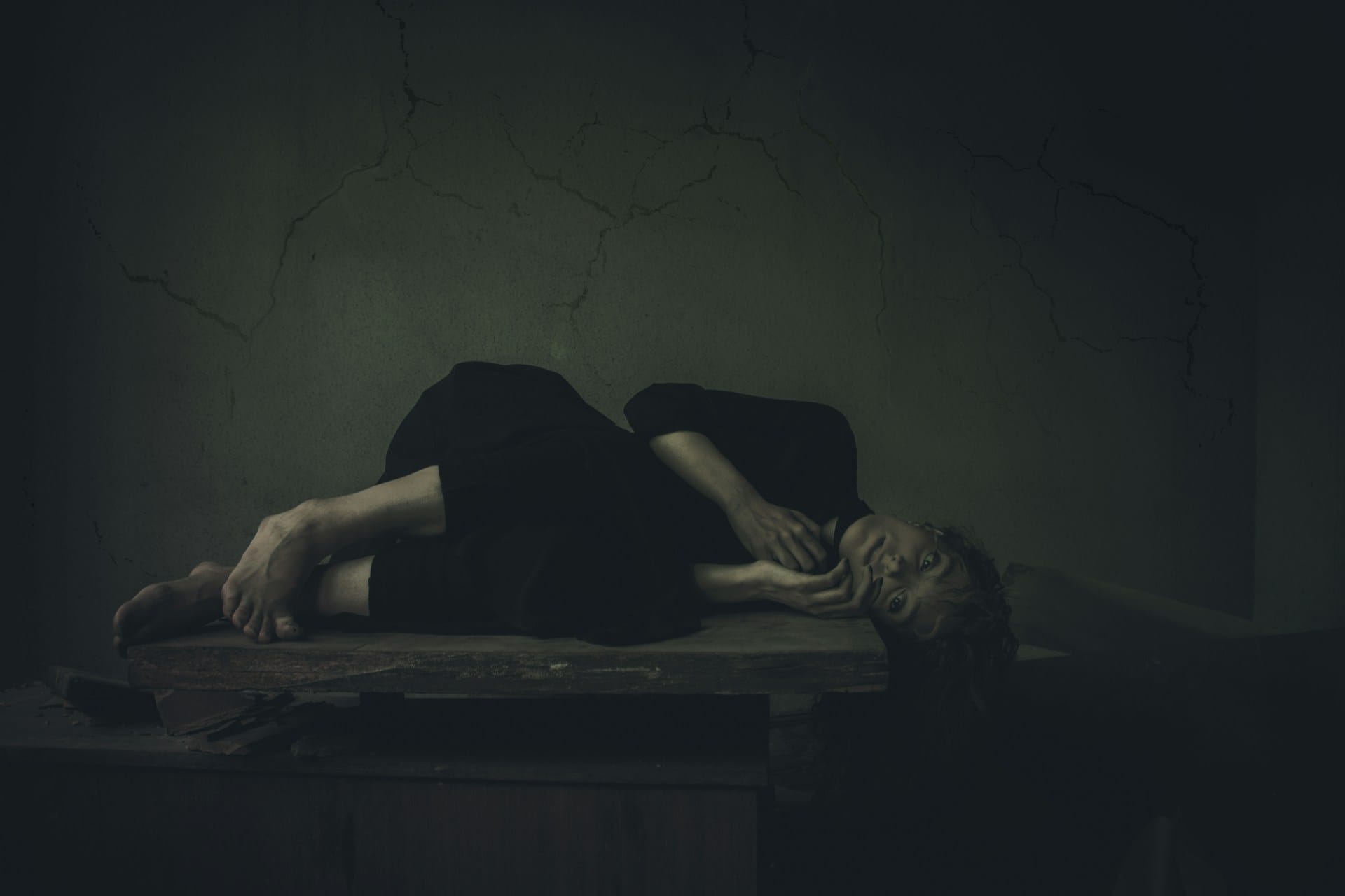 Une femme allongée en position fœtale sur une table.