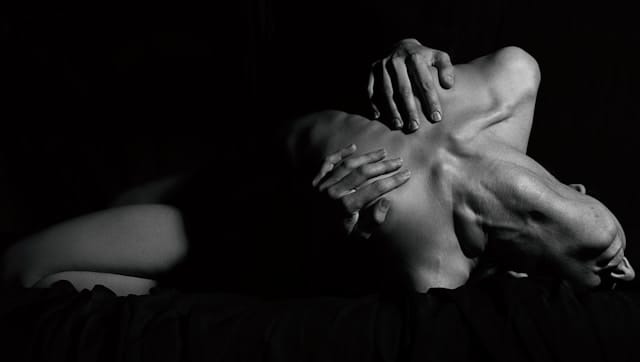 Photographie Lowkey d'une femme se cambrant de plaisir en masquant sa poitrine avec ses mains.