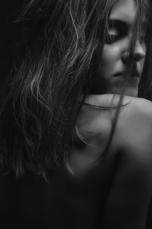 Femme de dos, dos nu, regardant en arrière par dessus son épaule.