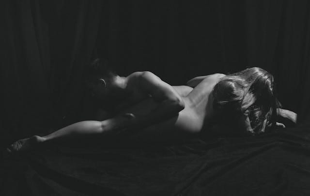 Nu artistique d'un couple tête bêche allongé sur un drap noir.