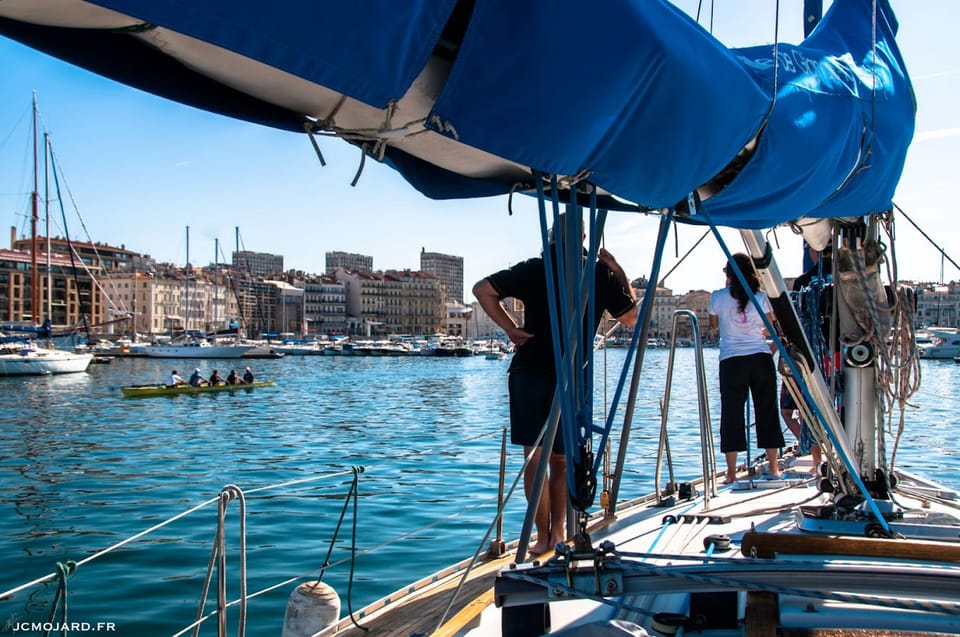 Des personnes sur le pont d'un voilier qui entre dans le port de Marseille.