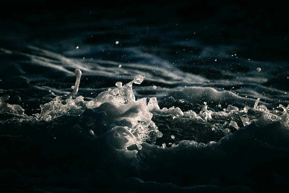 Une photo d'écume de mer dont certaines gouttes jaillissent au-dessus de la ligne de crête.