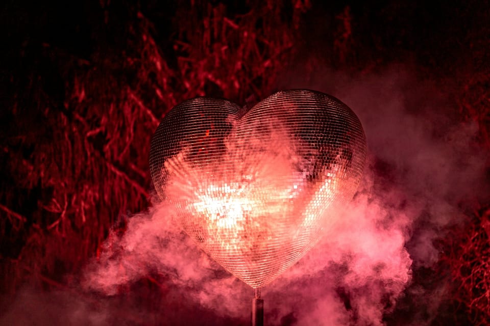 Une cœur sous la forme d'une boule scintillante disco, renvoie la lumière au milieu de la fumée.