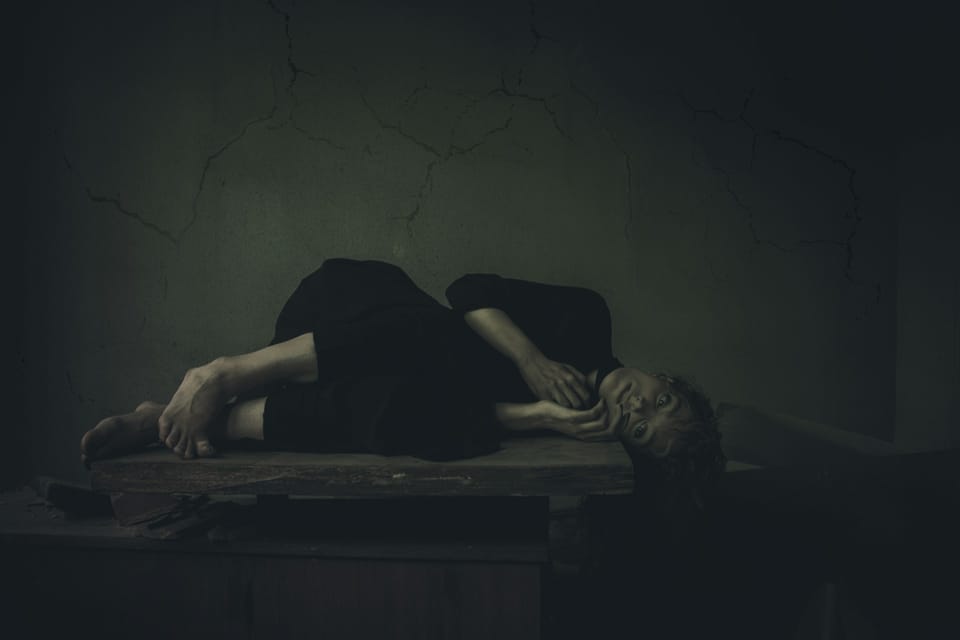 Une femme allongée en position fœtale sur une table.