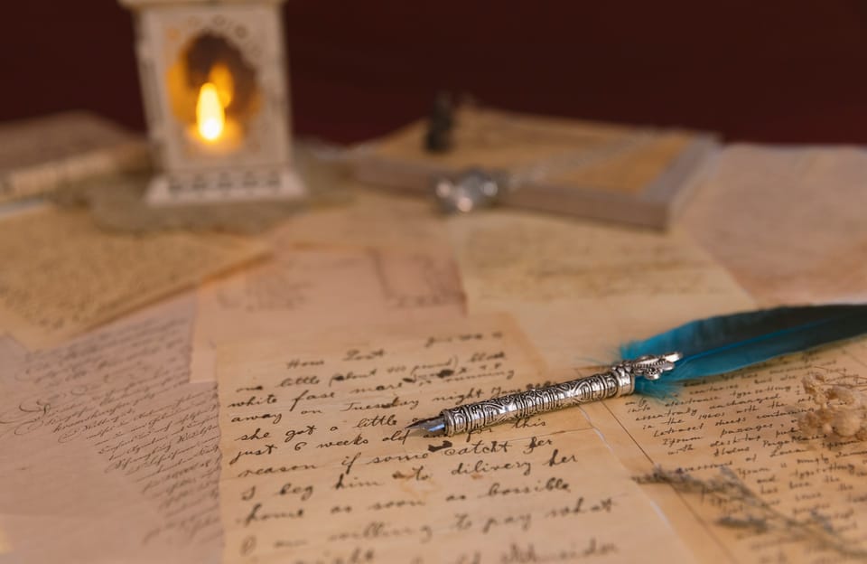 Une plume d'écriture en métal, posée sur des papiers griffonnés.