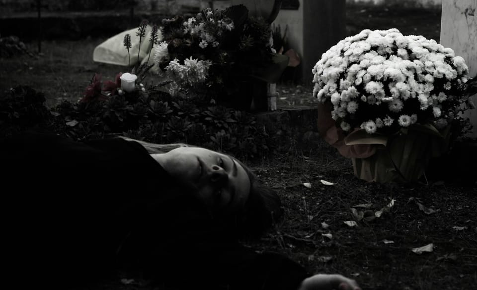 Une femme allongée devant une tombe.