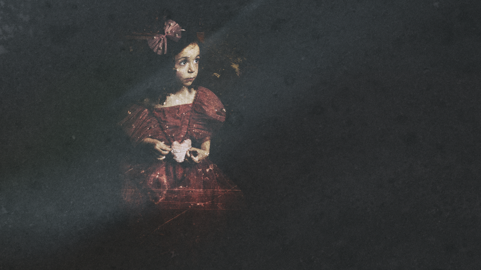 Une petite fille en belle robe de bal tenant un cœur en tissu dans ses mains.